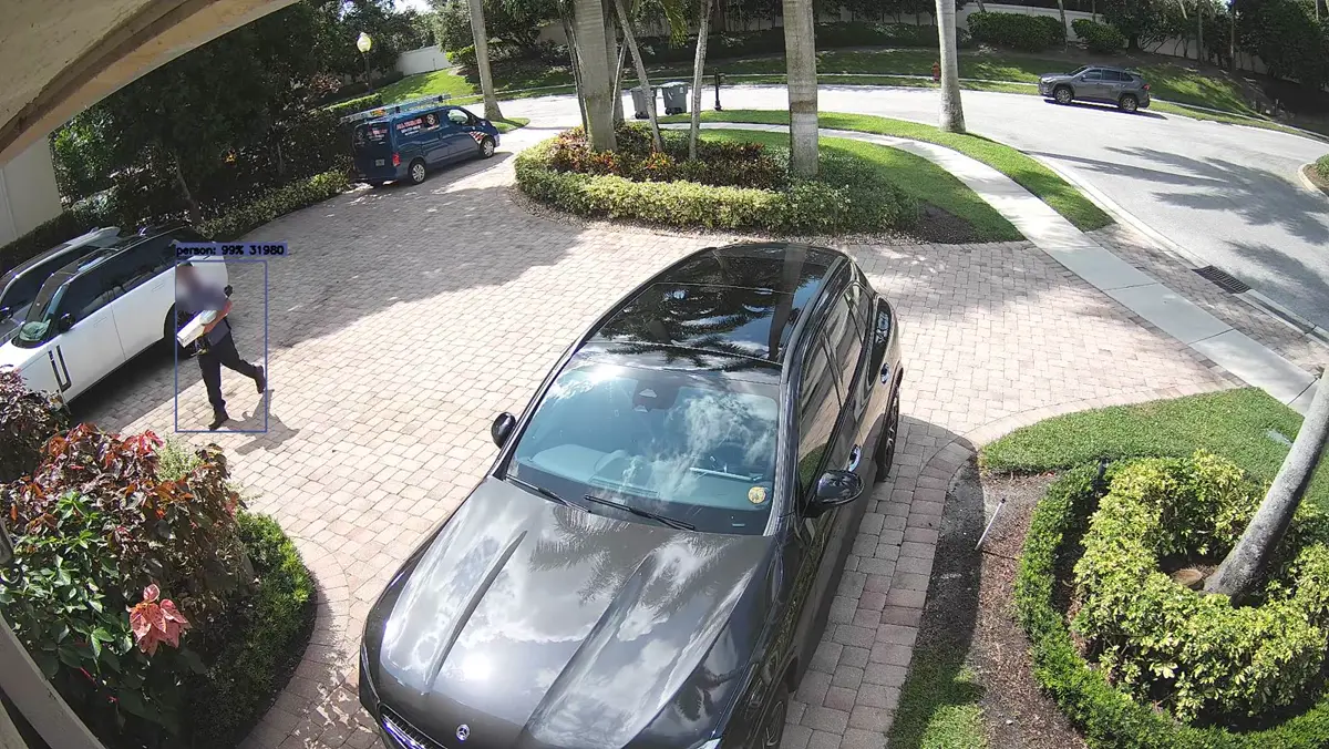 Driveway snapshot of a delivery person carrying a parcel, flagged by the AI audit pass